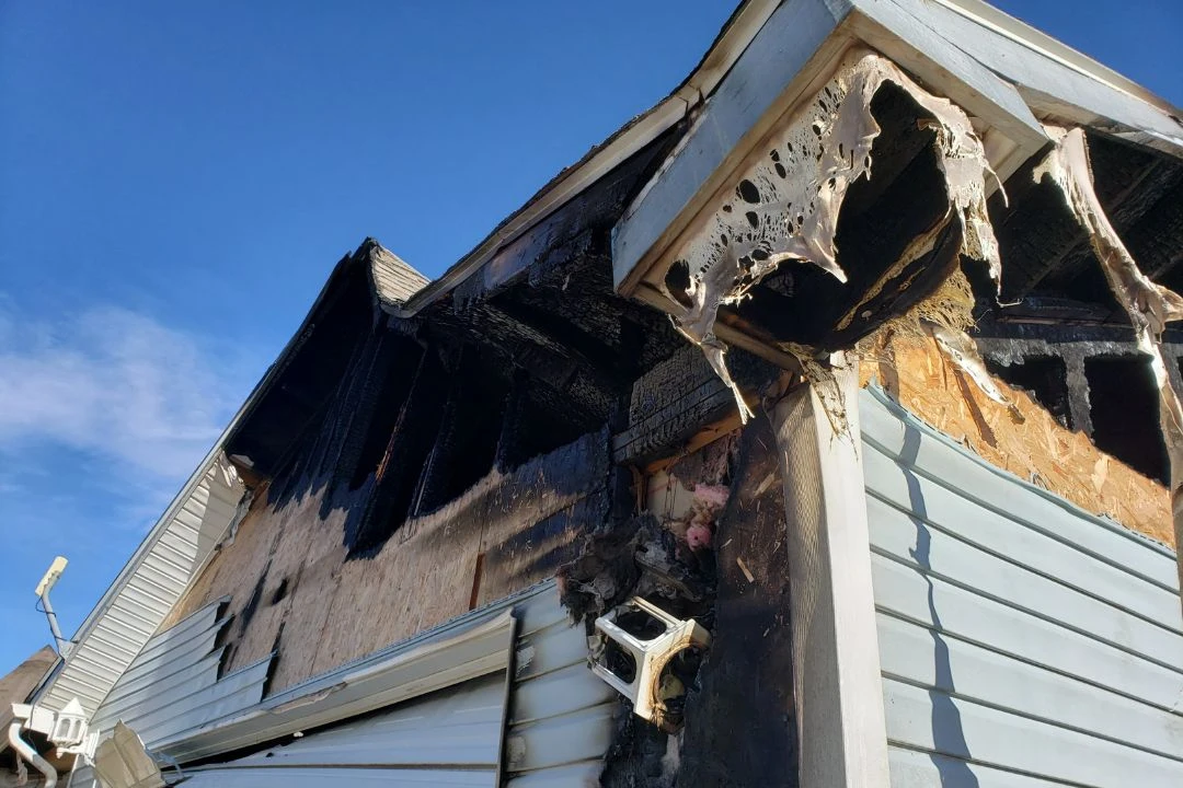 Severely burned residential building corner with exterior damage.